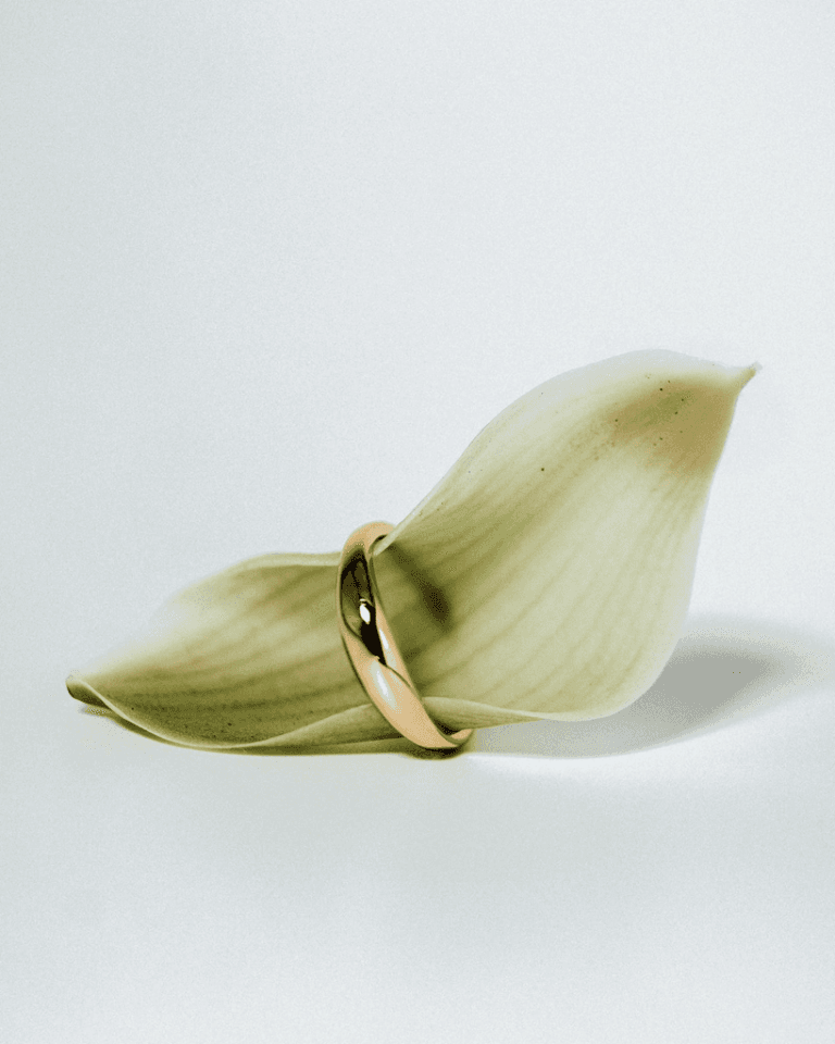 Aliança dourada de acabamento liso apresentada em uma flor